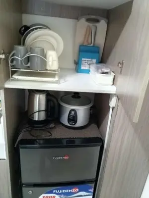 a small kitchen with a stove and other items on a shelf at Zafreen Condotel in Manila