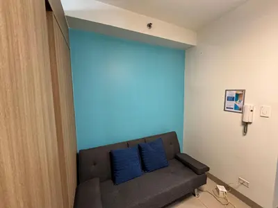 a couch with two blue pillows in a room at Room 643 Pool View Shore 2 Residences near PICC & SM MOA by Prime Stay in Manila