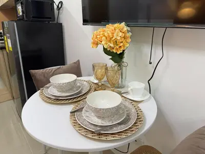 a white table with plates and cups and a vase of flowers at 640 Coffee Room Shore 2 Residences MOA Pool View by Prime Stay in Manila