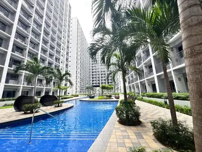 a swimming pool with palm trees and buildings at 1645 Coffee Room Shore 2 Residences Pool View by Prime Stay MOA in Manila