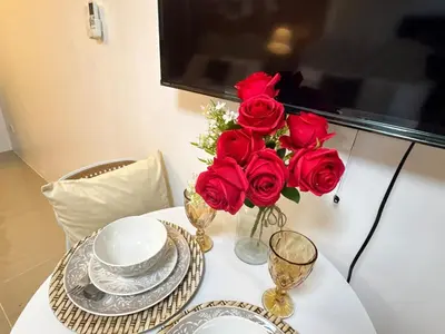 a table with a vase of red roses and plates at Coffee Room 1666 Shore 2 Residences Tower 1 Pool View by Prime Stay MOA in Manila