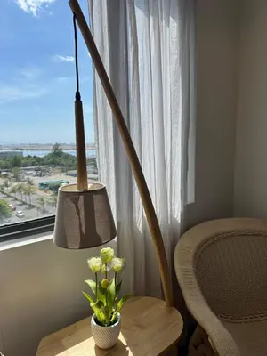 a table with a lamp and a chair next to a window at 2BR facing Manila Bay & City View Shore 2 Residences MOA with Parking by Prime Stay in Manila