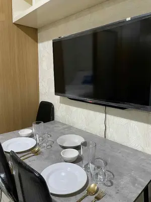 a table with plates and glasses and a television on a wall at Suite A Deluxe Near SM MALL OF ASIA in Manila