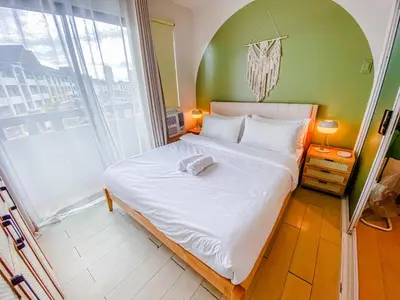 a bed in a room with a large window at Cozy Oasis Free pool, netflix, playground in Manila