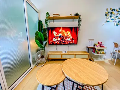 a living room with two tables and a tv on the wall at Cozy Oasis Free pool, netflix, playground in Manila