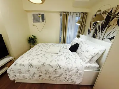 a small bedroom with a bed with a white comforter at The Camden Place 1BR Condo Apartment in Manila