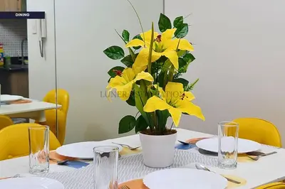 a table with a vase with yellow flowers on it at City View Staycation Near Mall of Asia and Airport in Manila