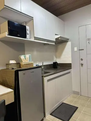 a small kitchen with white cabinets and a microwave at Stay at FB Harrison near World Trade Center MOA and NAIA in Manila
