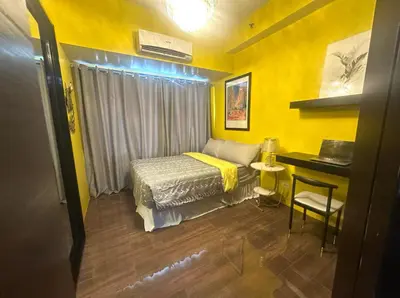a yellow bedroom with a bed and a desk at Cozy Escape by Dave 4563 in Manila