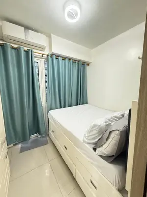 a bedroom with a bed with blue curtains at Shore 1 residences Tower D Pasay City in Manila