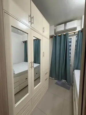 a bedroom with white cabinets and blue curtains at Shore 1 residences Tower D Pasay City in Manila