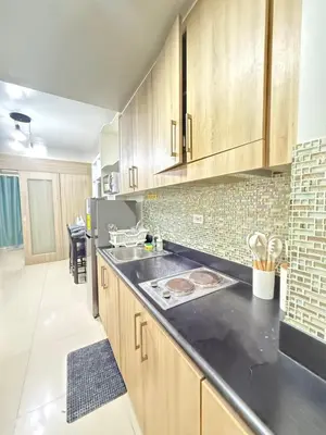 a kitchen with wooden cabinets and a black counter top at Shore 1 residences Tower D Pasay City in Manila