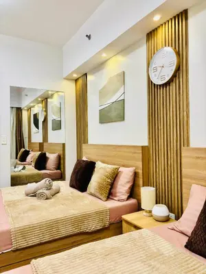a bedroom with two beds and a clock on the wall at Shore 2 Residences Tower 1 in Manila