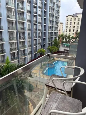 a balcony with a chair and a swimming pool at Cozy Haven Across Terminal 3 in Manila