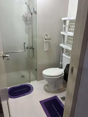 a bathroom with a toilet and a glass shower at Cozy Haven Across Terminal 3 in Manila