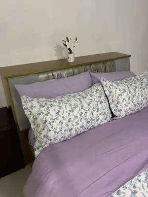 a bed with purple sheets and pillows with a plant on top at Cozy Haven Across Terminal 3 in Manila