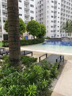 a pool with benches and a palm tree and buildings at Shore 1 Spacious Smart Home 3C in Manila