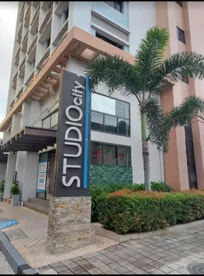 a sign in front of a building with a palm tree at Dagos Studio City Filinvest Alabang in Manila