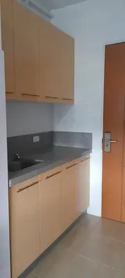 an empty kitchen with wooden cabinets and a sink at Dagos Studio City Filinvest Alabang in Manila