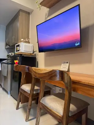 a television hanging on a wall above a table with two chairs at Erin Serenity Harbor in Manila