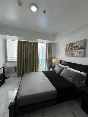 a bedroom with a large bed and a large window at Azure Resort and Staycation by Miss Angie in Manila