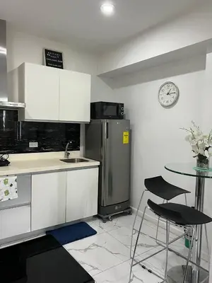 a kitchen with a refrigerator and a table and a clock at Azure Resort and Staycation by Miss Angie in Manila