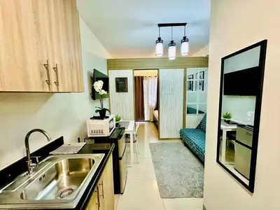 a kitchen with a sink and a living room at Shore Bliss Staycation MOA in Manila