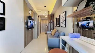 a living room with a blue couch and a tv at Cozy 1 Bedroom near MOA in Manila