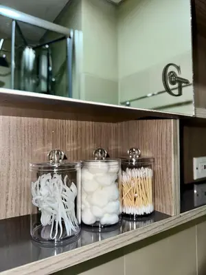 three glass jars on a shelf in a bathroom at GreyKey Stays at the 34th in Manila