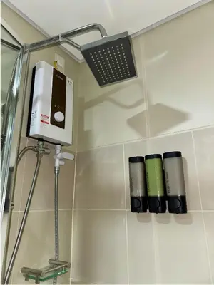 a bathroom with a shower with a laptop on the wall at GreyKey Stays at the 34th in Manila