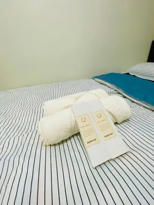 a bed with two towels and two tickets on it at Cabin and a cozy stay near MOA in Manila
