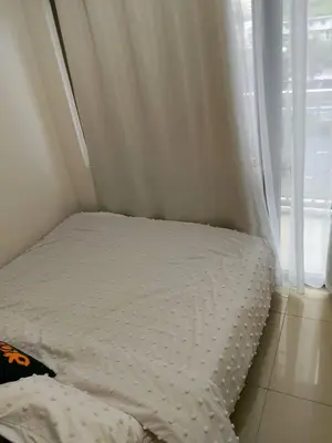 a bed with white sheets and a window at Ambulinog in Manila