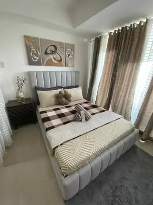 a bedroom with a large bed with a checkered blanket at Condo in Paranaque City Homes Azure in Manila