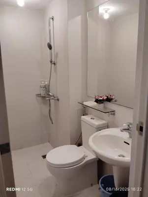 a white bathroom with a toilet and a sink at Condo in Paranaque City Homes Azure in Manila