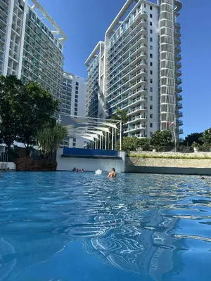 a person swimming in a pool in front of buildings at Condo in Paranaque City Homes Azure in Manila