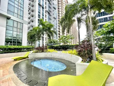 a patio with a hot tub with yellow chairs and trees at The Viceroy Tower Staycation at McKinley Hills Taguig in Manila