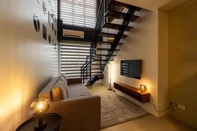 a living room with a couch and a staircase at Stunning View Loft Type 1 BR in Circulo Verde near Bridgetowne, Eastwood Fast Wi-Fi in Manila
