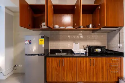 a kitchen with wooden cabinets and a stainless steel refrigerator at Stunning View Loft Type 1 BR in Circulo Verde near Bridgetowne, Eastwood Fast Wi-Fi in Manila
