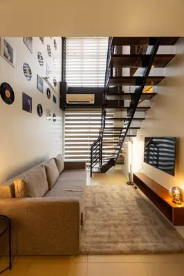 a living room with a couch and a staircase at Stunning View Loft Type 1 BR in Circulo Verde near Bridgetowne, Eastwood Fast Wi-Fi in Manila