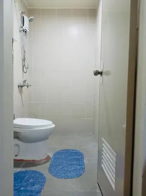 a bathroom with a toilet and a shower with blue rugs at JFam Suites, C2-5F 1BR , Up To 6 Pax in Biñan