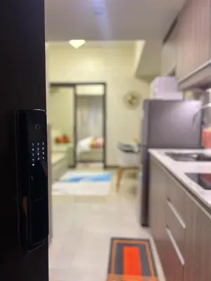 a kitchen with a refrigerator and a living room at Luxe 1BR Condo - Near BGC & Venice Grand Canal in Manila