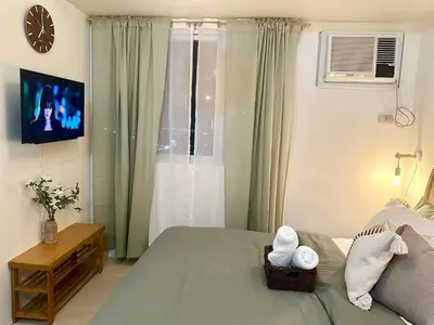 a bedroom with a bed with a television and a window at Captivating Crib in the Metro in Manila