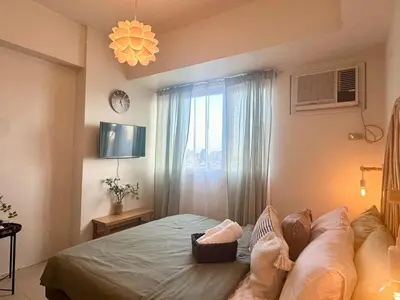 a bedroom with a bed and a window with a clock at Captivating Crib in the Metro in Manila