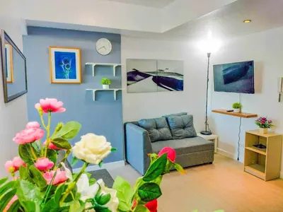 a living room with a couch and a clock on the wall at Azure Place Maui 8th floor in Manila