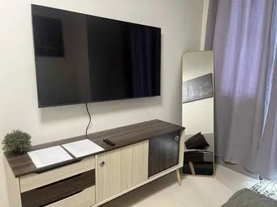 a living room with a television on a wall at The Calm Corner - S Residences Tower 2 in Manila