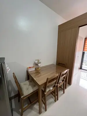 a dining room with a wooden table and chairs at Calle Homes - 1BR unit with balcony, LUSH RESIDENCES in Manila