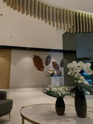 a living room with two vases with flowers on a table at Calle Homes - 1BR unit with balcony, LUSH RESIDENCES in Manila
