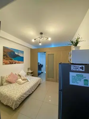 a living room with a bed and a refrigerator at Haven's Suites a place like home in Manila