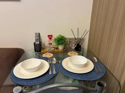 a glass table with plates and utensils on it at Haven's Suites a place like home in Manila