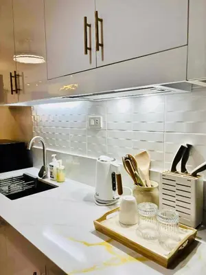 a kitchen with white cabinets and a tray of dishes at Sea Residences in Manila